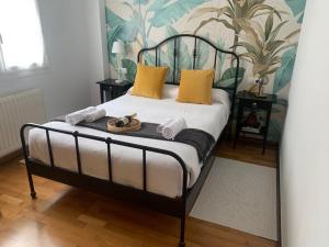 Una cama con almohadas amarillas y toallas. en Apartamento con encanto y mucha luz, en Villaviciosa