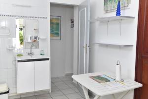 una cucina bianca con tavolo e lavandino di Coco et Canne a Port-Louis