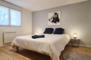 een witte slaapkamer met een groot bed met blauwe kussens bij L'échappée Belle in Bessines