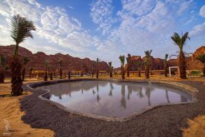 a small pond in the middle of a desert with palm trees at Sahary Al Ula Resort in AlUla