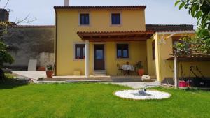 a yellow house with a fountain in the yard at Leutoño in Malpica