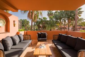 a patio with couches and a table and palm trees at Apartamento La Perla in Marbella