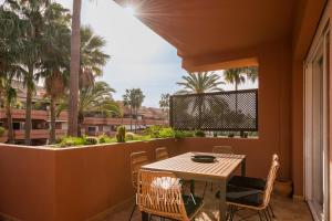 a balcony with a table and chairs and palm trees at Apartamento La Perla in Marbella