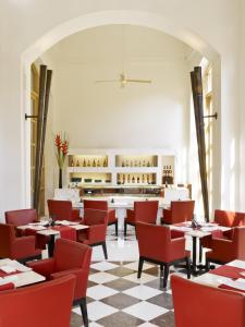 a dining room with tables and red chairs at Trident Gurgaon in Gurgaon