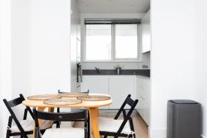 una pequeña cocina con mesa de madera y sillas en Modern Brixton Apartment, en Londres