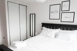 Cette chambre comprend un lit avec des draps blancs et deux miroirs. dans l'établissement Modern Brixton Apartment, à Londres
