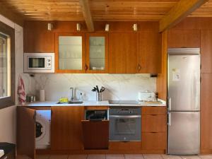 a kitchen with wooden cabinets and a stainless steel refrigerator at Jarandín 27 - Adosado familiar en Biescas in Biescas