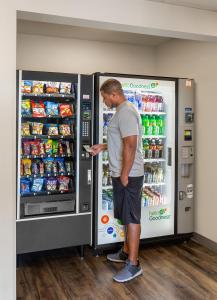un homme debout devant un distributeur automatique de boissons dans l'établissement WoodSpring Suites Omaha Bellevue, an Extended Stay Hotel, à Bellevue