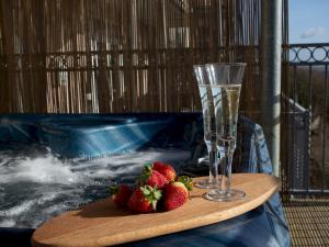 a wooden table with strawberries and a glass of champagne at Pass the Keys Pendine hot tub sea views in Carmarthen