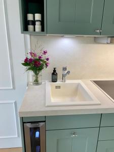 a kitchen counter with a sink and flowers in a vase at Süderhygge in Keitum +21 photos