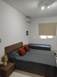 een slaapkamer met een bed met 2 oranje kussens bij Hampton Court, Block C, n.2 in St Paul's Bay