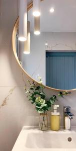 a bathroom sink with a mirror and a vase with flowers at Apartament Botanica - Blisko parku i centrum - by SpaceApart in Jelenia Góra