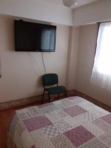 1 dormitorio con 1 cama, 1 silla y TV de pantalla plana en Cielo Patagónico en Trelew