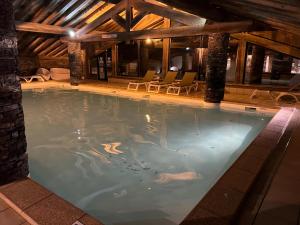 une piscine intérieure avec des chaises dans un bâtiment dans l'établissement Appartement ski aux pieds dans résidence premium piscine, sauna hamam, aux Menuires