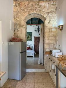 una cocina con nevera y una habitación con 1 dormitorio en בית האבן העתיק מ-1885 en Rosh Pinna