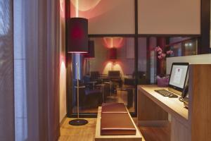 a room with a desk with a computer and a dining room at IntercityHotel Leipzig in Leipzig