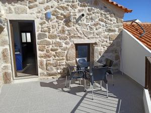 un patio con mesa y sillas frente a un edificio de piedra en Isabel de Gouveia en Belmonte