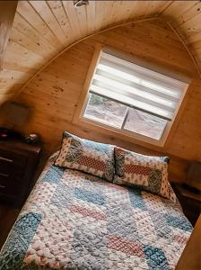a bedroom with a quilt on a bed with a window at Hillside Cottages in Bay Roberts