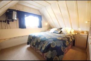 a bedroom with a bed with a blue comforter and a window at 3bedroom beautiful cottage in Cheshunt