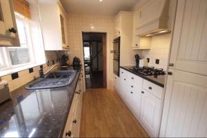 una cocina con armarios blancos y fregadero en 3bedroom beautiful cottage, en Cheshunt