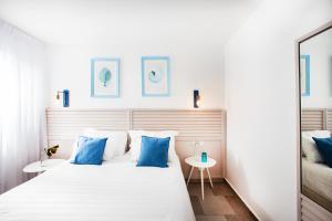 a bedroom with a large white bed with blue pillows at Nachsholim Beach Hotel in Nahsholim