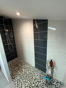 uma casa de banho com um chuveiro com azulejos pretos e brancos em L’océan 20 em Queyrac