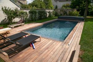a swimming pool on a wooden deck with a table and a bench at Le Clos de Gally in Chavenay