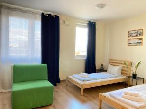 シュチェチンにあるResidence Aparthotelのベッド2台と緑の椅子が備わる客室です。