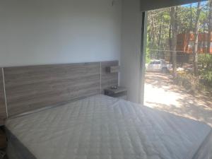 1 cama en un dormitorio con ventana grande en Bosque loan en Balneario Mar Azul