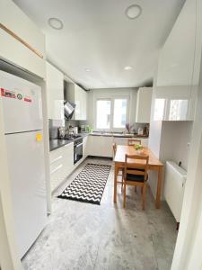 a white kitchen with a table and a refrigerator at NEW BUILDING Lovely Modern Apt with 90mbs fiber internet 5min walking to Bagdat Street in Istanbul