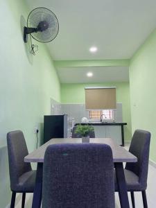 a room with a table with chairs and a fan at Sri Aman Homestay in Jitra