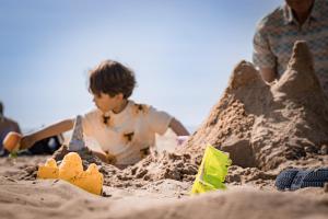 a young boy playing in a sand castle on the beach at Hotel Neptunus in Egmond aan Zee