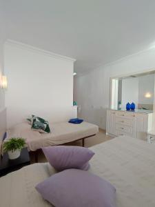 Habitación blanca con 2 camas y espejo. en Apartamento primera línea - Playa Patalavaca, en Patalavaca