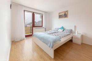 a white bedroom with a bed and a window at Apartment Mountain Sunrise in Škofja Loka