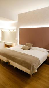um quarto com uma cama grande e lençóis brancos em Hotel Ocamiño em Durango