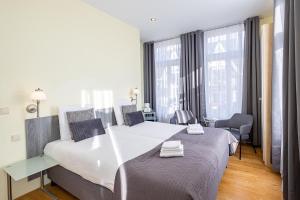 Cette chambre comprend un grand lit et une chaise. dans l'établissement Hotel Mare Liberum, à Egmond aan Zee