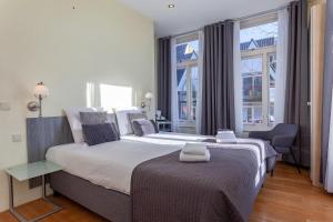 a bedroom with a large bed and a large window at Hotel Mare Liberum in Egmond aan Zee