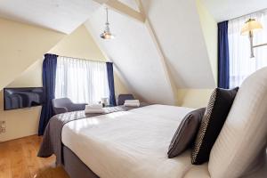 a bedroom with a large bed and a chair at Hotel Mare Liberum in Egmond aan Zee