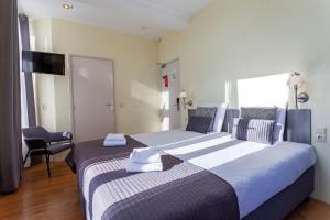 une chambre d'hôtel avec deux lits et une chaise dans l'établissement Hotel Mare Liberum, à Egmond aan Zee