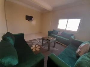 sala de estar con sofás verdes y mesa en Dar Inn Raha 1, en Laayoune