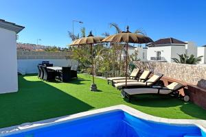 un patio con sedie e ombrelloni accanto alla piscina di Villa Namaste ad Adeje