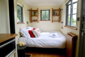 a small bedroom with a white bed with pillows at The Shepherd's Hut @ Chichester Cottage in Chichester