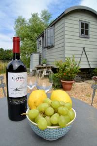 a bottle of wine and a bowl of grapes on a table at The Shepherd's Hut @ Chichester Cottage in Chichester