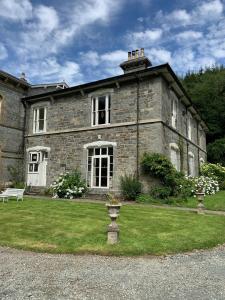 an old stone house with a bench in the yard at Riverside apartment in Betws-y-coed