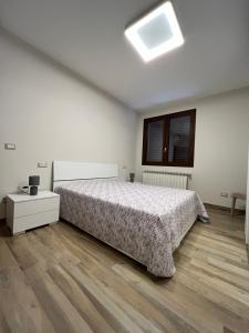 biała sypialnia z łóżkiem i drewnianą podłogą w obiekcie Casa vacanze Rosemary w mieście Nardò