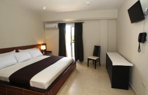 a bedroom with a bed and a desk and a television at La Costa Playa El Agua Hotel in El Agua