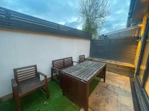 a patio with two chairs and a wooden bench at 2a Seymour Road in Hackbridge