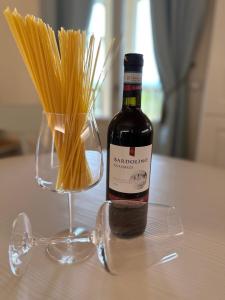 a bottle of wine sitting next to a vase of spaghetti at Green Living Apartment in Pozzolengo