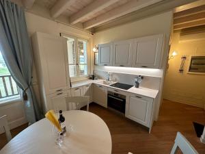 a kitchen with white cabinets and a table at Green Living Apartment in Pozzolengo