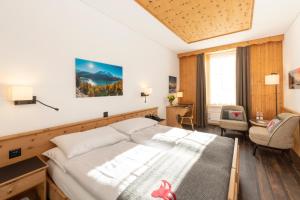 um quarto de hotel com uma cama e uma cadeira em Edelweiss Swiss Quality Hotel em Sils Maria